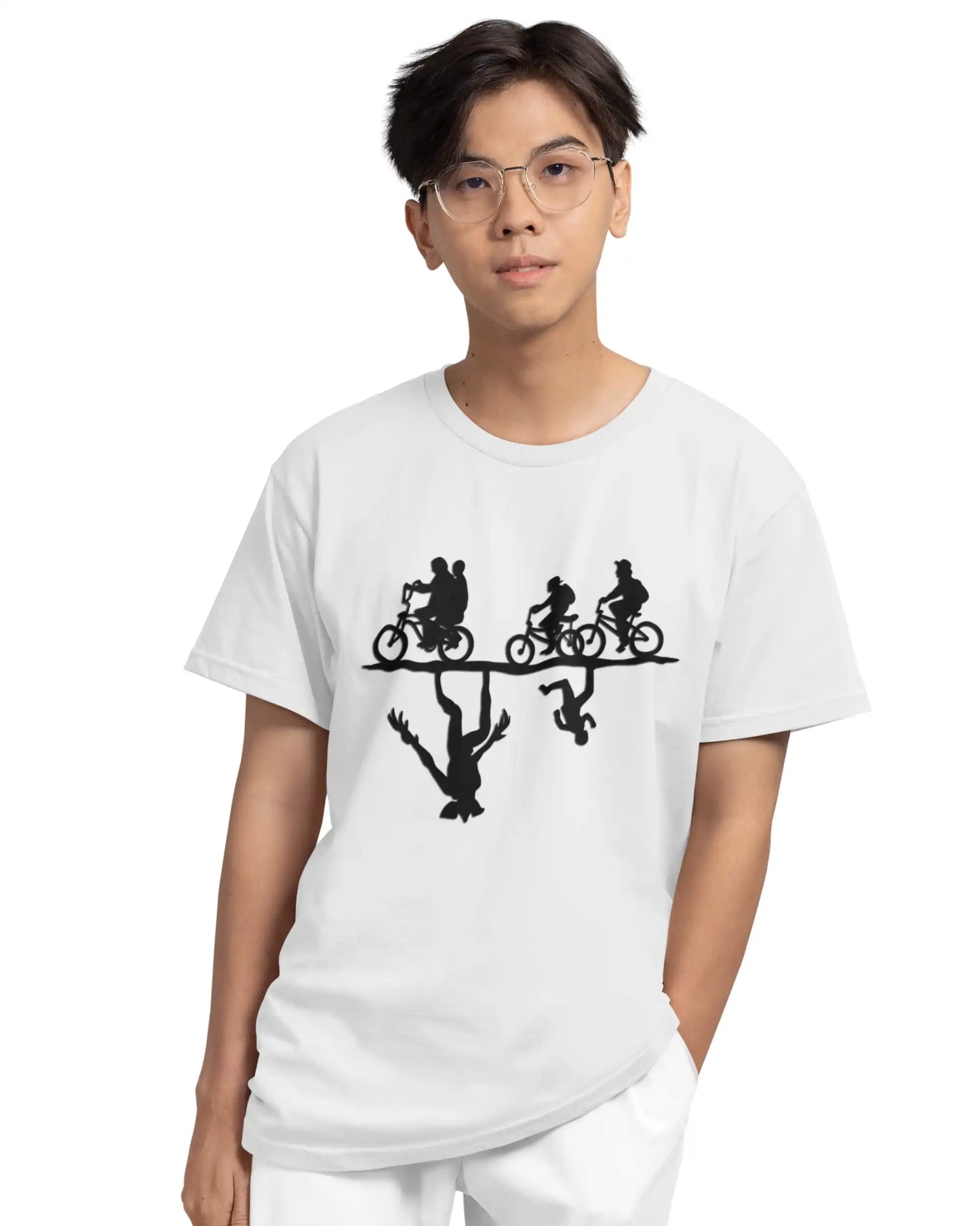 Young man wearing AWBlack white Stranger Things graphic t-shirt with black cast biking silhouette Unleash the Upside Down design, oversized fit