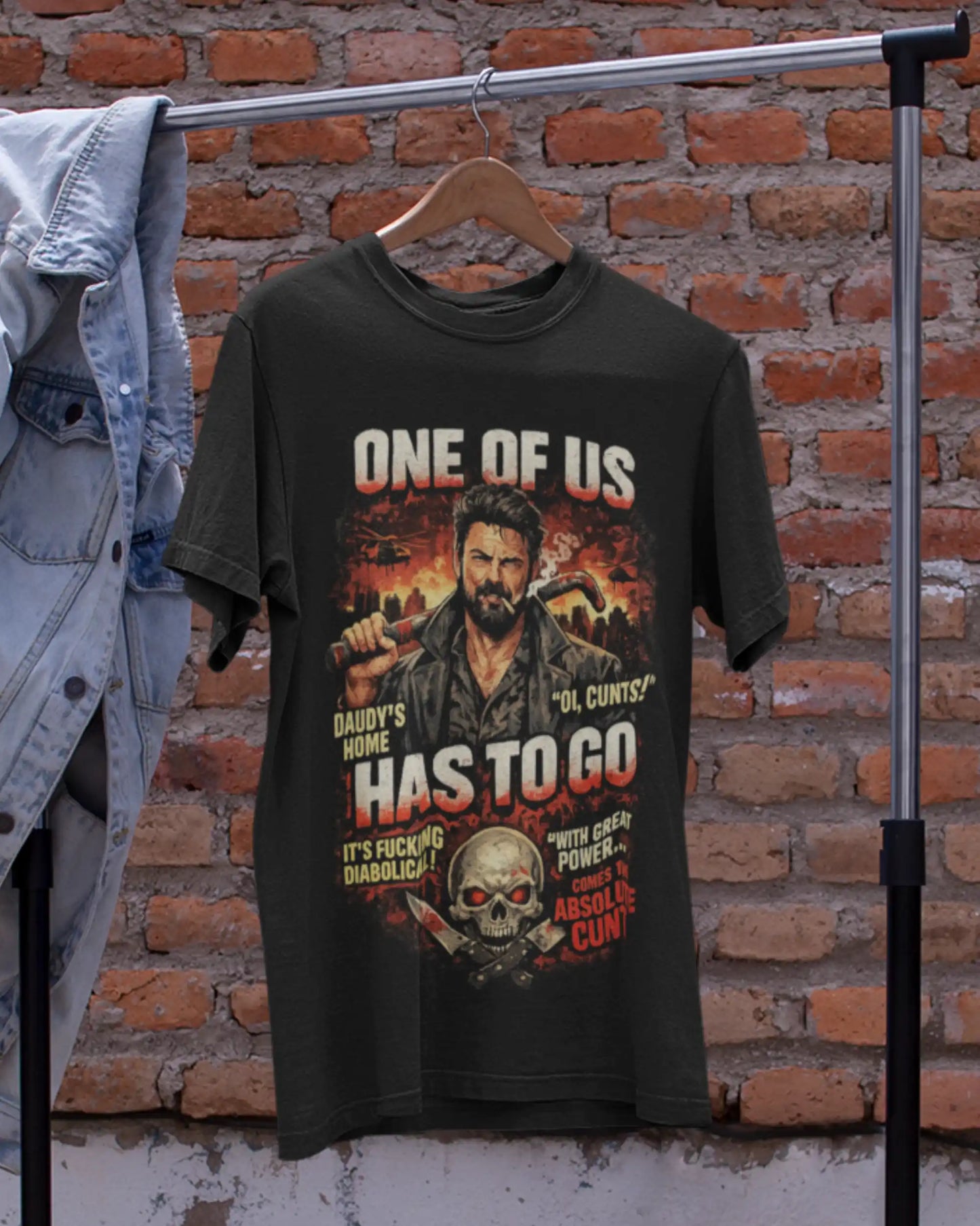 Black plus size t-shirt with 'One of Us' movie graphic design, displayed on a hanger against a brick wall background