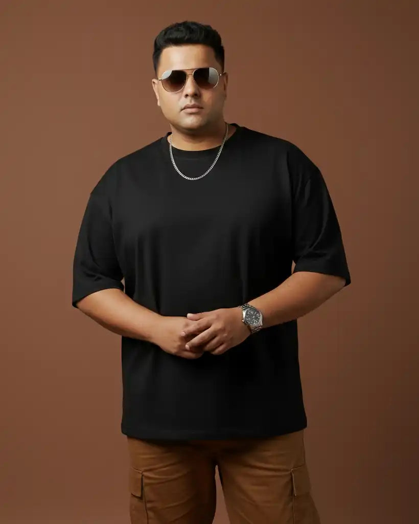Plus size black oversized t-shirt on plus size male model wearing sunglasses, front view against brown background, premium AWBlack plain tee