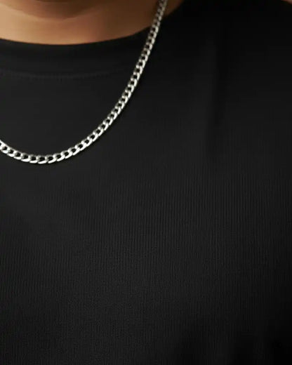 Close-up of silver chain necklace on plus size black oversized t-shirt neckline, premium AWBlack plain tee fabric detail