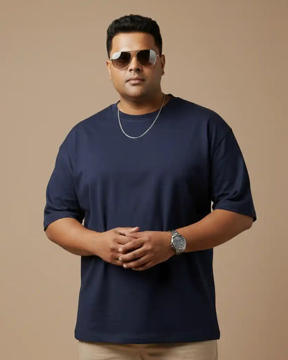 Plus size navy blue oversized t-shirt on plus size male model wearing chain necklace and sunglasses, arms crossed front view against beige background, premium AWBlack plain tee