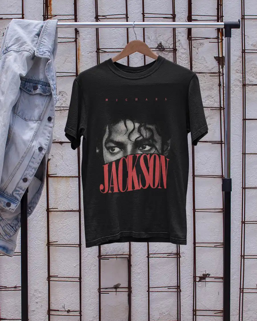 AWBlack Michael Jackson Eyes Vintage Typography Graphic T-Shirt in Black hanging on wooden hanger beside denim jacket | Premium 180 GSM Cotton | Multi-Fit Regular, Oversized & Plus Size S–7XL | Music Streetwear Tee for Men